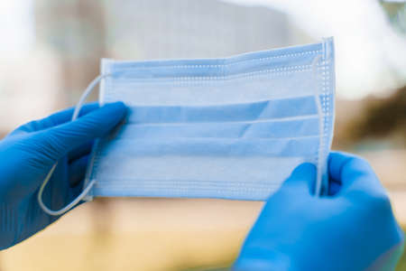 Man hold blue medical mask in medical gloves to protect from epidemy of virus.