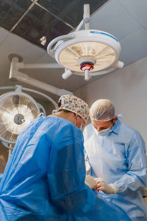 Blepharoplasty plastic surgery operation for modifying the eye region of the face in medical clinic. 2 doctors do plastic cosmetic operation for woman. Surgeon sutures the eyelidの写真素材