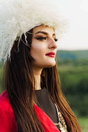 Georgian girl with national flag of Georgia in hands on blue sky background. Georgian culture...