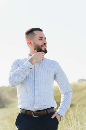 Handsome bearded arabian man in sunglasses on the green hills background. Confident muslim business man. Arab man weared in white shirtの写真素材