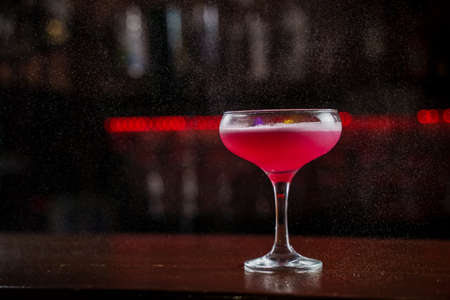 Classic Pink Lady cocktail closeup with flower and cherry on bar counterの写真素材