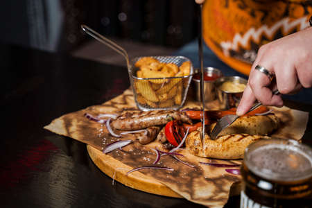 Barbecue grilled hot dog with yellow mustard and ketchup on wooden background. Hot dog sandwich with potato fries and sauces.の写真素材