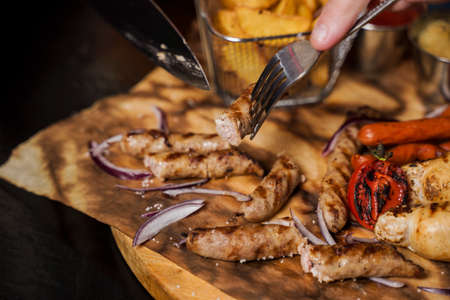 Barbecue grilled hot dog with yellow mustard and ketchup on wooden background. Hot dog sandwich with potato fries and sauces.の写真素材