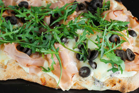 Pinsa romana close-up. gourmet italian cuisine on black background. Scrocchiarella traditional dish....