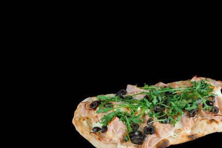 Pinsa romana gourmet italian cuisine on black background. Scrocchiarella traditional dish. Food delivery from pizzeria. Pinsa with meat, arugula, olives, cheese.の写真素材