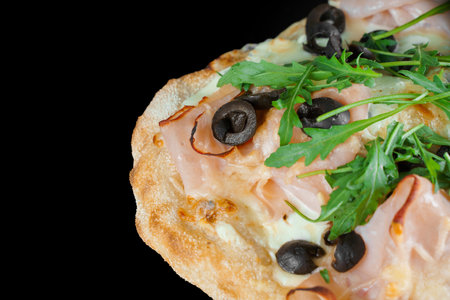 Pinsa romana close-up. gourmet italian cuisine on black background. Scrocchiarella traditional dish. Food delivery from pizzeria. Pinsa with meat, arugula, olives, cheese.の写真素材