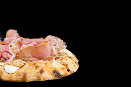 Scrocchiarella with pear, cheese, prosciutto on black background. Pinsa romana gourmet italian cuisine. Food delivery from pizzeria. Junk foodの写真素材