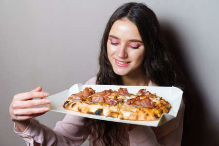 Girl courier with pinsa romana gourmet italian cuisine on gray background. Holding scrocchiarella...