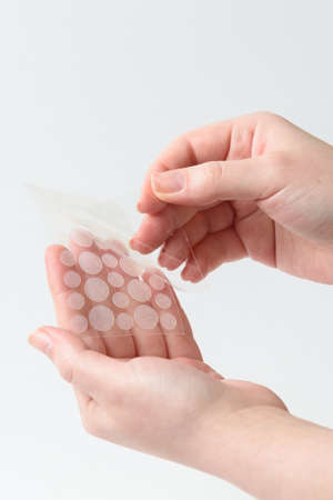 Round patches for acne and wrinkles on the hands on a white background. Acne and wrinkle patches for...