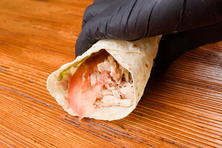 Burrito making process. The chef wraps stuffed pita on a wooden table. Mexican dish.の写真素材