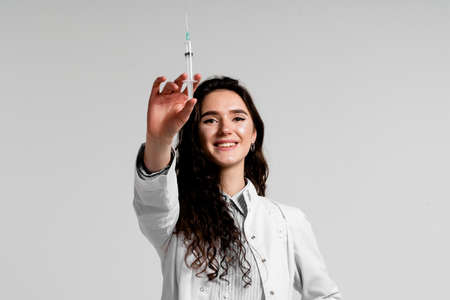 Doctor holding syringe with coronavirus vaccine. Covid-19 Vaccination. Stop quarantine. Attractive girl in medical gloves with syringe and medicationの写真素材