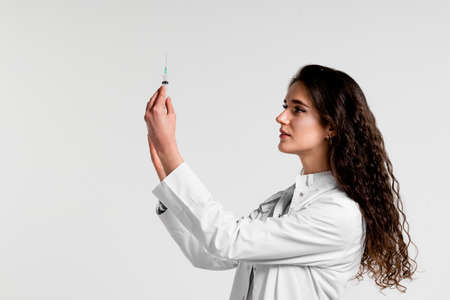 Doctor holding syringe with coronavirus vaccine. Covid-19 Vaccination. Stop quarantine. Attractive girl in medical gloves with syringe and medicationの写真素材