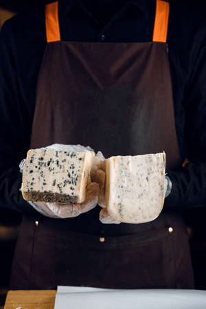 Blue cheese and gouda with italian herbs in hands. Holding dorblu, gorgonzola, roquefort. French gourmet traditional cuisine.の写真素材