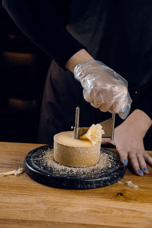 Shaving tete de moine cheese using girolle knife. Variety of Swiss semi-hard cheese made from unpasteurized cows milk, the name Monks headの写真素材