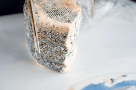 String for slicing blue cheese. Mix of cheeses on plate. Slicing dorblu, gorgonzola, roquefort. French gourmet traditional cuisine.の写真素材