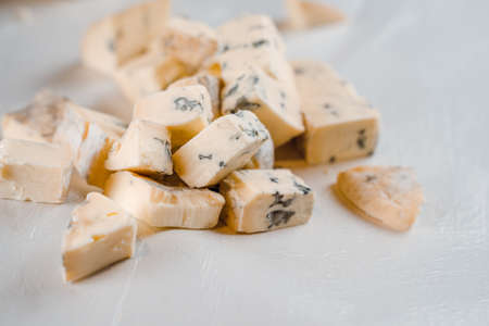 Mix of cheeses on plate. Slicing blue cheese dorblu, gorgonzola, roquefort. French gourmet traditional cuisine.の写真素材