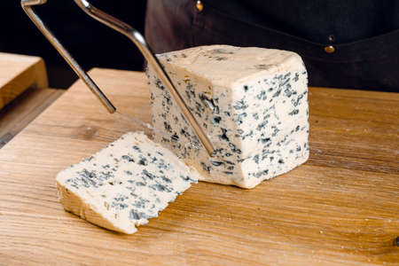 String for slicing blue cheese. Mix of cheeses on plate. Slicing dorblu, gorgonzola, roquefort. French gourmet traditional cuisine.の写真素材