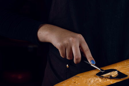 Slicing aged cheese parmesan with crystals using a slicer knife. Hard cheese with knife on dark background. Snack tasty piece of food for appetizerの写真素材