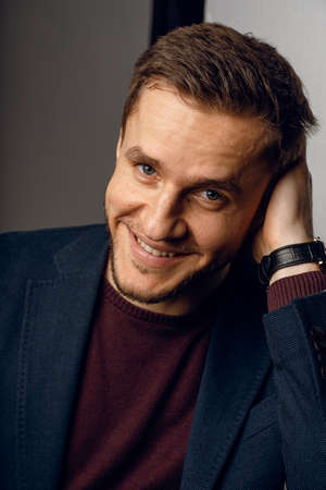 Confident male smiling. Business man portrait on dark background. Handsome young man weared suit in...