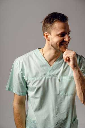 Surgeon weared in medical robe smile and posing on white background. Handsome happy doctor posing in...
