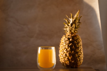 Pineapple fruit and juice in double glass cup. Tropical fruit. Pouring yellow tropical juice into glass.の写真素材