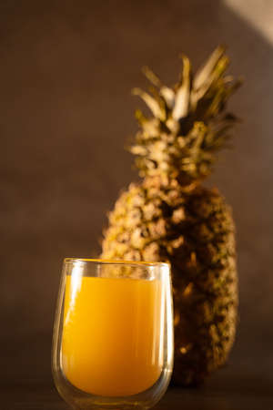 Pineapple fruit and juice in double glass cup. Tropical fruit. Pouring yellow tropical juice into glass.の写真素材
