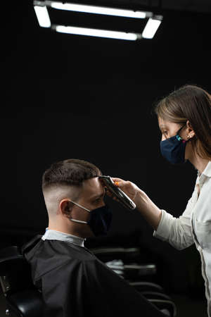 Barbershop customer in medical mask for protection against virus  Making hairstyle for handsome manの写真素材