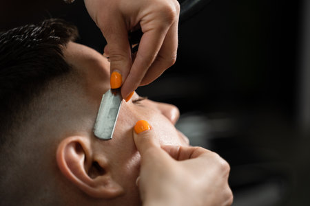 Straight razor cut man hair in barbershop. Attractive woman barber making hairstyle for handsome manの写真素材