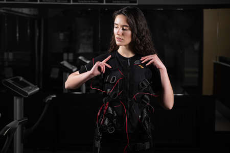 Girl in EMS suit in gym. Sport training in electrical muscle stimulation suitの写真素材