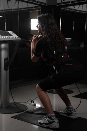 Girl in EMS suit in gym. Sport training in electrical muscle stimulation suitの写真素材
