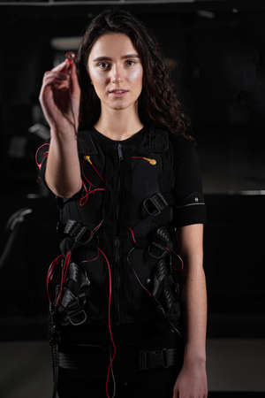 Girl with electronic contactor of EMS suit in gym. Sport training in electrical muscle stimulation suitの写真素材