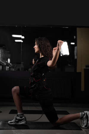 Making physical exercises using EMS suit in gym. Sport training in electrical muscle stimulation suitの写真素材