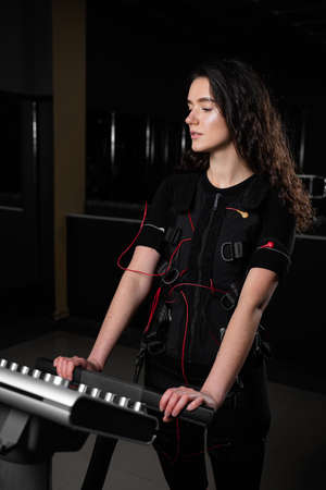 Girl in EMS suit in gym. Sport training in electrical muscle stimulation suitの写真素材