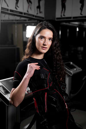 Girl in EMS suit in gym. Sport training in electrical muscle stimulation suitの写真素材