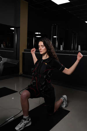 Making physical exercises using EMS suit in gym. Sport training in electrical muscle stimulation suitの写真素材