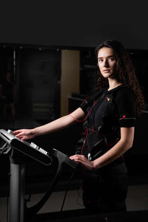 Girl in EMS suit in gym. Sport training in electrical muscle stimulation suitの写真素材