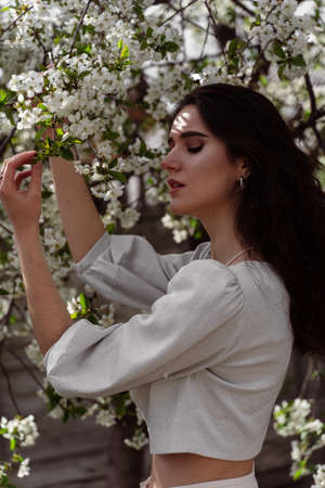Lovely girl near blooming trees in the park. Outdoor walking in at sunny day. Lifestyle of young womanの写真素材