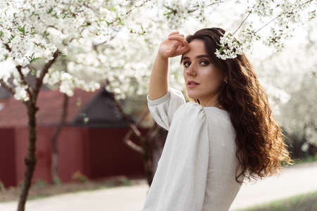 Lovely girl near blooming trees in the park. Outdoor walking in at sunny day. Lifestyle of young woman.の写真素材