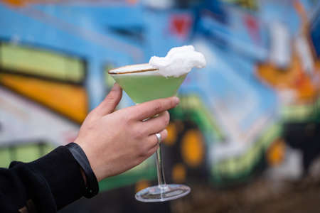 Green alcohol cocktail in glass decorated with cotton candy on color backgroundの写真素材