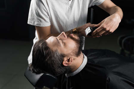 Trimming the beard with a shaving machine. Advertising for barbershop and men's beauty salon.の写真素材
