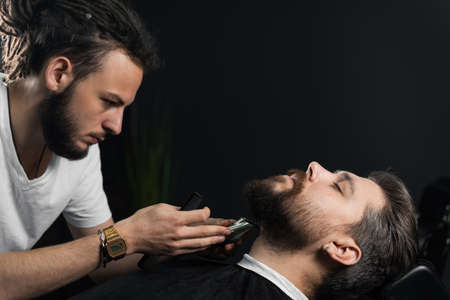 Trimming the beard with a shaving machine. Advertising for barbershop and men's beauty salon.