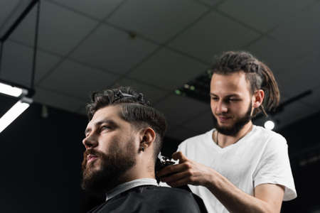 Low fade machine haircut for handsome bearded man in barbershop. Hair cut with a smooth transitionの写真素材