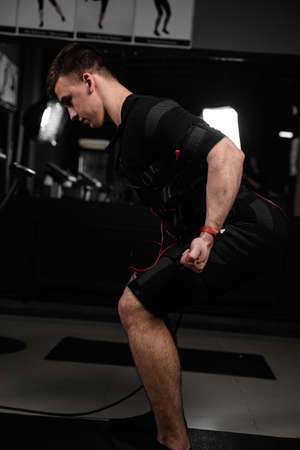 Making physical exercises using EMS suit in gym. Sport training in electrical muscle stimulation suit.の写真素材