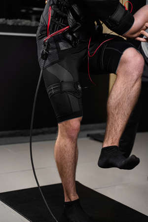 Making physical exercises using EMS suit in gym. Sport training in electrical muscle stimulation suit.の写真素材