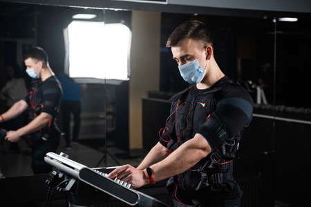 Man in EMS suit and medical mask in gym.
