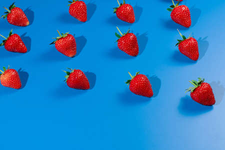 Strawberry ripe fruit on blue background. Harvest of fresh red berry.