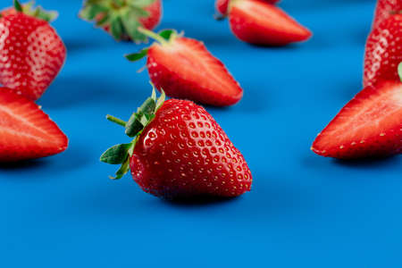 Strawberry slices and whole strawberries on blue background. Seasonal berryの写真素材