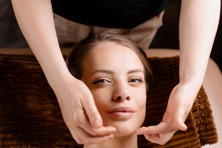 Masseur is making facial massage in spa for model with perfect skin. Beauty procedureの写真素材