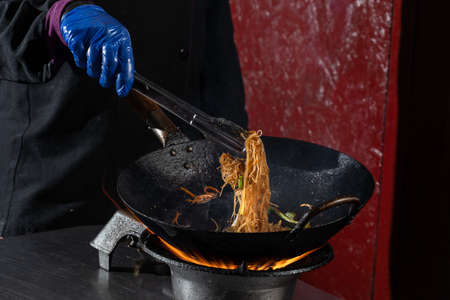 Funchoza flambe rice noodles with vegetables cooking on fire in wok pan. Street foodの写真素材