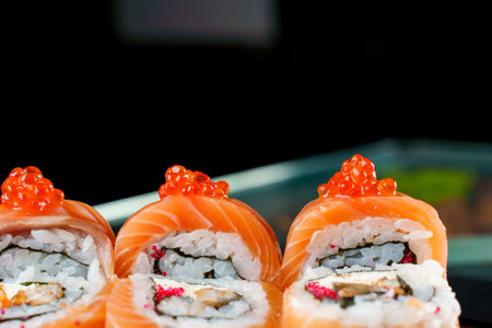 Roll red dragon with salmon, red caviar, tobiko, eel, rice, nori close-up. Sushi traditional...